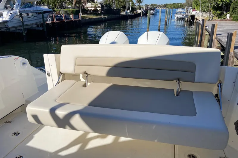Slide: The Image of 2024 Boston Whaler 320 Vantage boat with comfortable seating, docked by a scenic waterfront. - 3