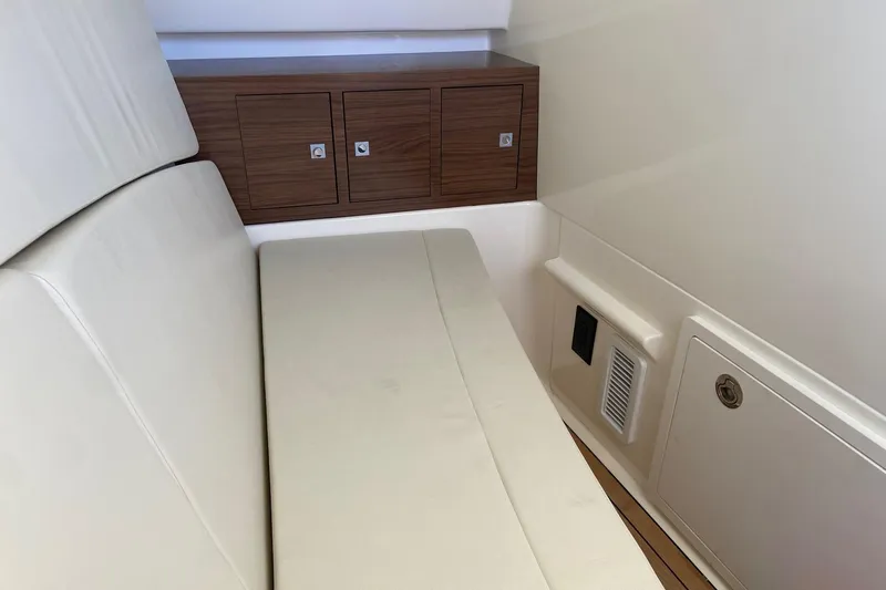 Slide: The Image of 2024 Boston Whaler 320 Vantage interior with cushioned seating and wooden storage cabinets. - 38