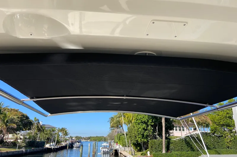 Slide: The Image of 2024 Boston Whaler 320 Vantage boat with sunshade, docked near palm trees and waterfront homes. - 41