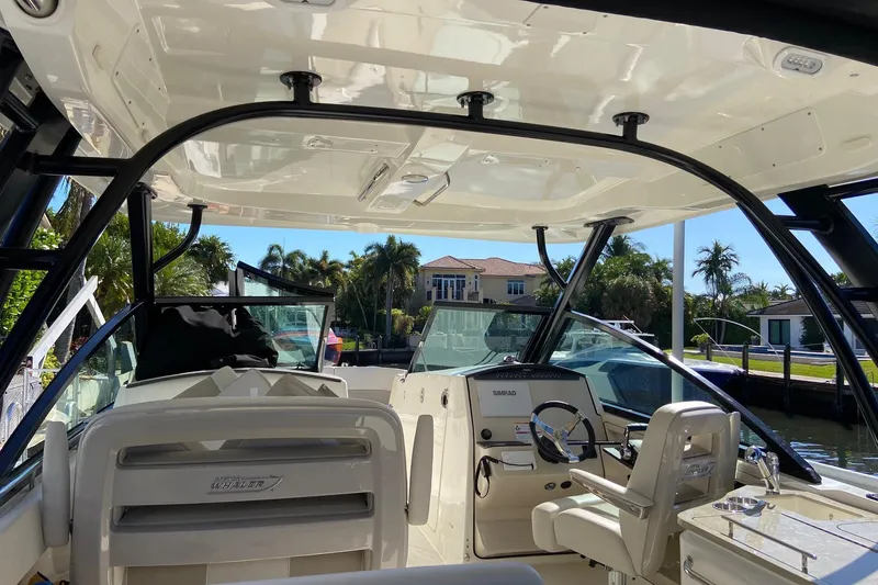 Slide: The Image of 2024 Boston Whaler 320 Vantage boat interior with helm and seating, docked near waterfront homes. - 45