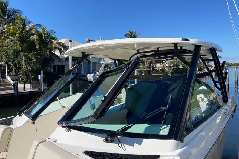 Slide: The Image of 2024 Boston Whaler 320 Vantage boat docked, featuring sleek windshield design. - 50
