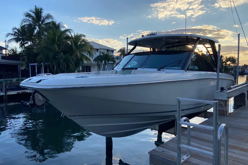 Slide: The Image of 2024 Boston Whaler 320 Vantage boat docked at sunset with palm trees in background. - 51