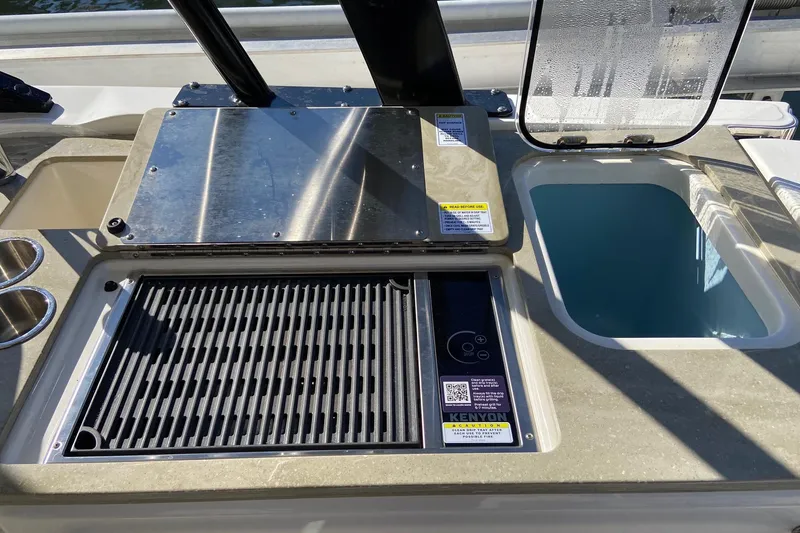 Slide: The Image of 2024 Boston Whaler 320 Vantage boat grill and sink setup, featuring Kenyon grill. - 8