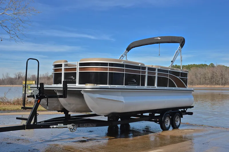 Slide: The Image of 2019 Bennington 21 SSX pontoon boat on trailer by a lake. - 10