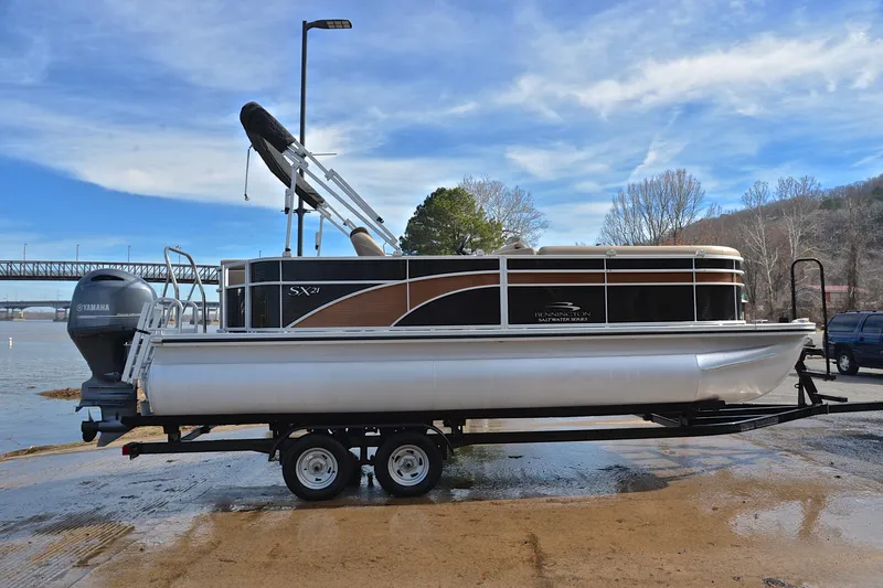 Slide: The Image of 2019 Bennington 21 SSX pontoon boat on trailer by a riverbank. - 15
