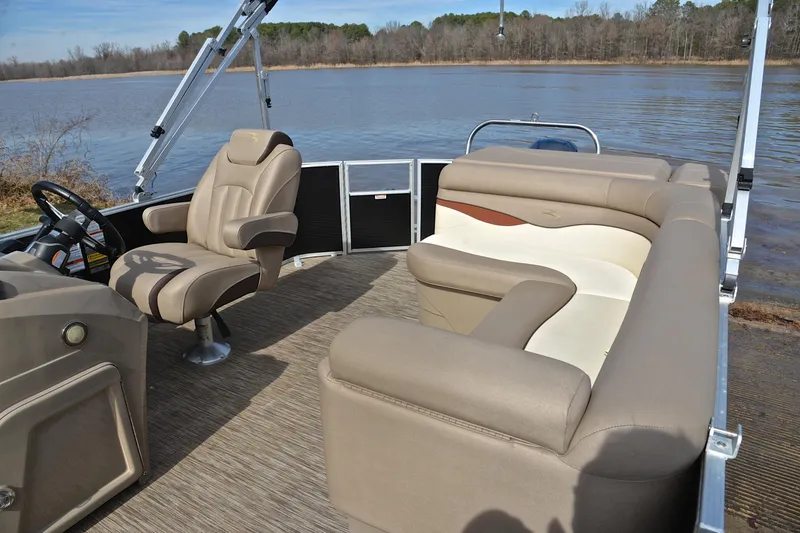 Slide: The Image of 2019 Bennington 21 SSX pontoon boat interior with beige seating, steering console, and lake view. - 22