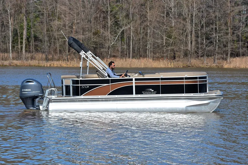 Slide: The Image of 2019 Bennington 21 SSX pontoon boat cruising on a calm lake. - 6