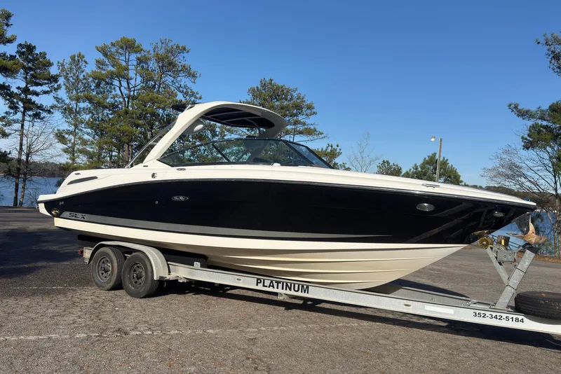 Slide: The Image of 2008 Sea Ray 270 SLX boat on trailer, parked near a lake with trees. - 2