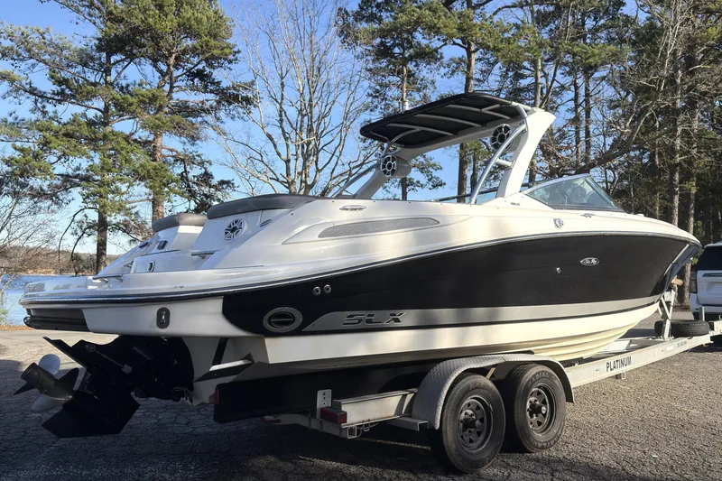 Slide: The Image of 2008 Sea Ray 270 SLX boat on trailer, parked near a lake with trees in the background. - 21