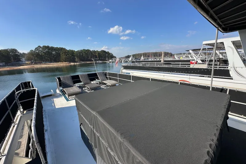 Slide: The Image of 2004 Lakeview 16x68 houseboat on serene lake with lounge chairs and clear blue sky. - 16