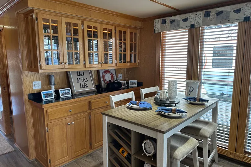 Slide: The Image of Dining area in 2004 Lakeview 16x68 houseboat with wooden cabinets and table setting. - 5