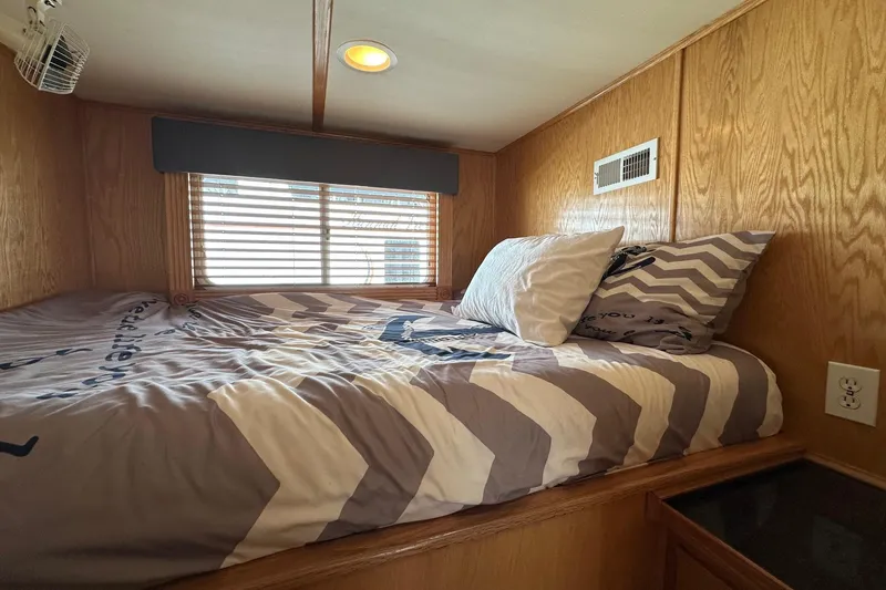 Slide: The Image of Cozy bedroom in 2004 Lakeview 16x68 houseboat with chevron bedding and wood paneling. - 6