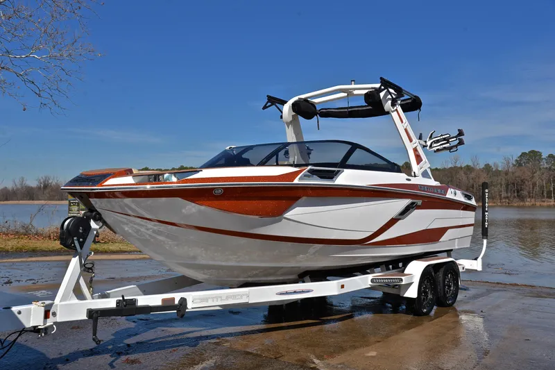 Slide: The Image of 2023 Centurion Ri230 boat on trailer by a lake, showcasing sleek design and modern features. - 12