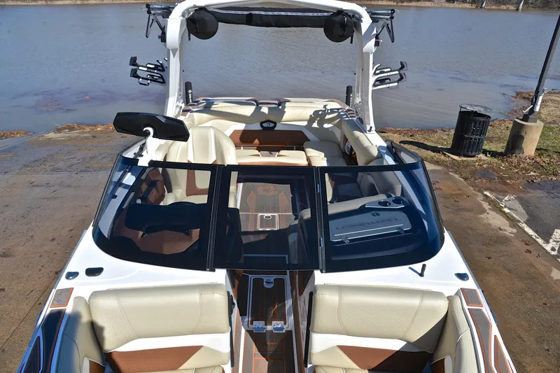 Slide: The Image of 2023 Centurion Ri230 boat interior with beige seating, docked by a lake. - 22