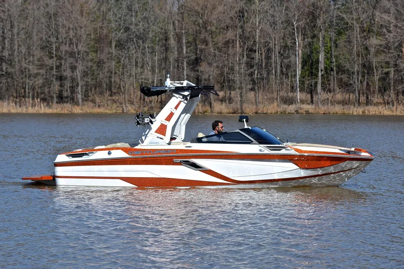 Slide: The Image of 2023 Centurion Ri230 boat cruising on a calm lake with wooded shoreline. - 8