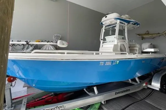 Slide: The Image of 2020 Everglades 243 Center Console boat in a garage, blue hull, on a trailer. - 20