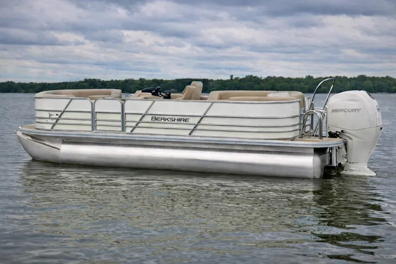 The Image of 2026 Berkshire 22 RFX LE pontoon boat on a calm lake with Mercury engine. - 1