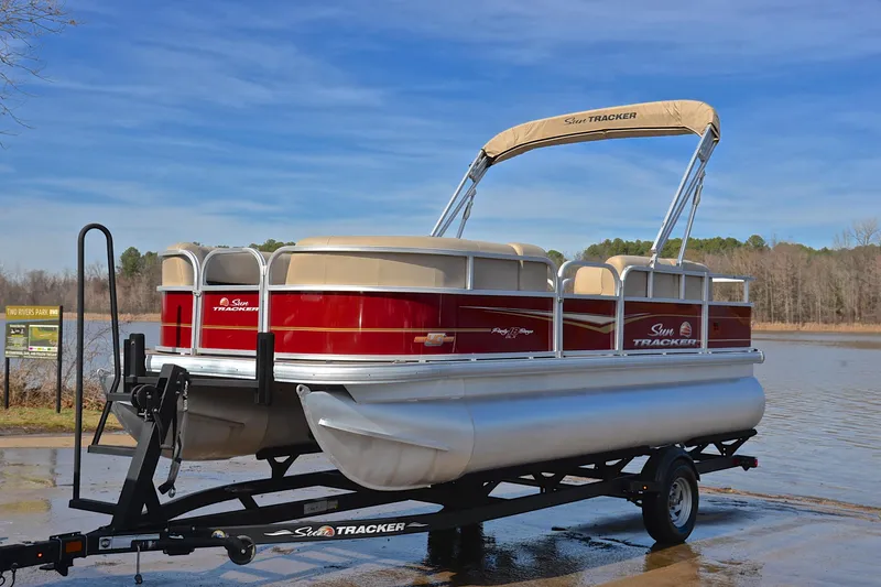 Slide: The Image of 2023 Sun Tracker Party Barge 18 DLX pontoon boat on trailer by a lake. - 10