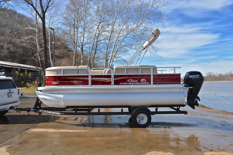 Slide: The Image of 2023 Sun Tracker Party Barge 18 DLX pontoon boat on trailer by a lake. - 11