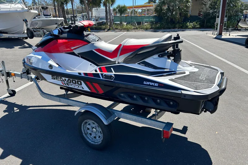 Slide: The Image of 2012 Sea-Doo Wake 155 jet ski on trailer, parked in sunny lot. - 4