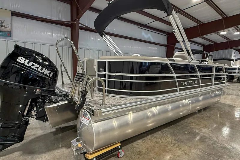 Slide: The Image of 2025 Trifecta 22RF LE pontoon boat with Suzuki outboard motor in a showroom. - 2