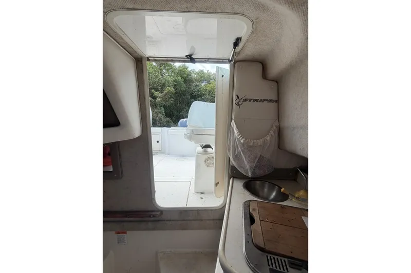 Slide: The Image of Interior view of 2002 Seaswirl 2101 boat, featuring a compact kitchenette and open cabin door. - 14