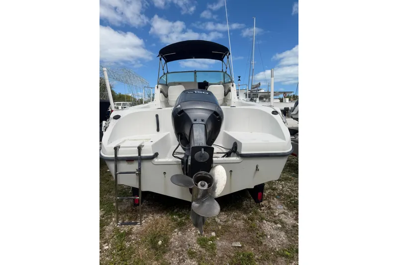 Slide: The Image of 2002 Seaswirl 2101 boat with outboard motor, docked on grassy area under blue sky. - 3