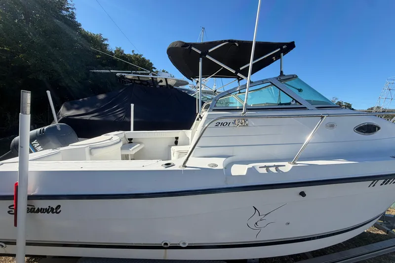 Slide: The Image of 2002 Seaswirl 2101 boat with canopy, docked outdoors under clear blue sky. - 1