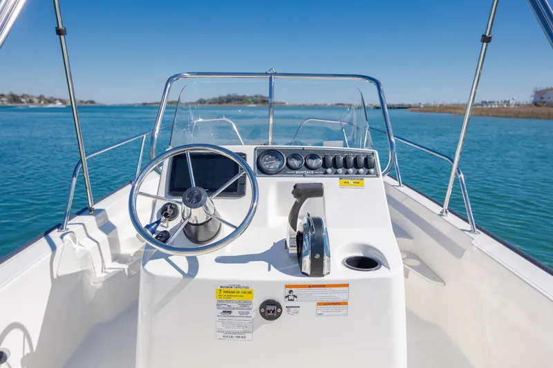 Slide: The Image of 2018 Boston Whaler 170 Montauk boat console with steering wheel on calm water. - 15