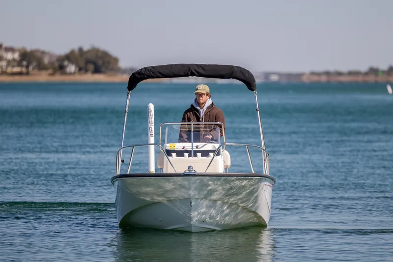 Slide: The Image of 2018 Boston Whaler 170 Montauk boat on calm water, with a person steering. - 4