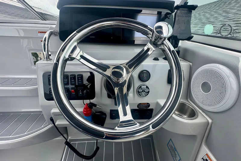 Slide: The Image of 2025 Regal 26 XO boat helm with chrome steering wheel and control panel. - 32