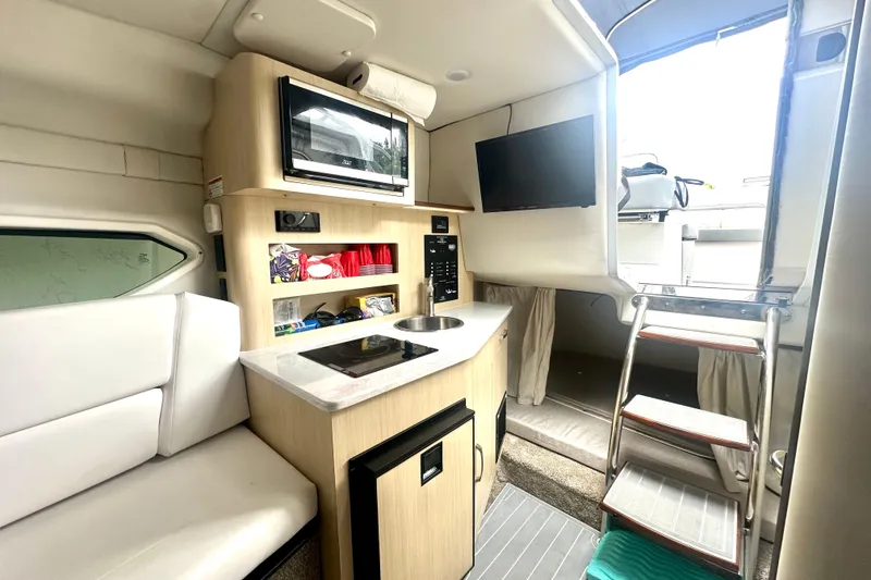 Slide: The Image of Interior of 2025 Regal 26 XO boat with kitchenette, microwave, and seating area. - 43