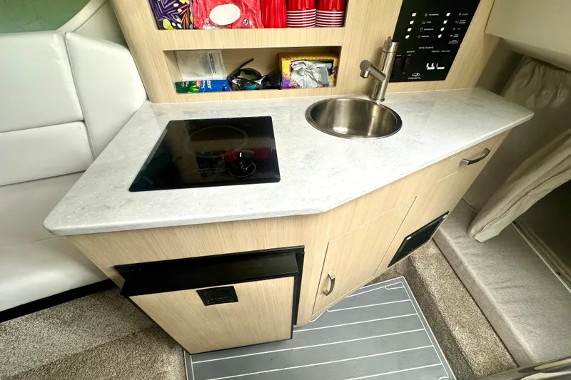 Slide: The Image of 2025 Regal 26 XO boat interior with kitchenette, featuring a sink and stovetop. - 45