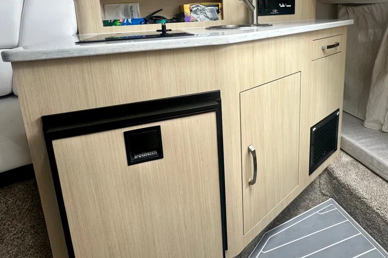 Slide: The Image of 2025 Regal 26 XO boat interior kitchenette with sink and storage cabinets. - 47