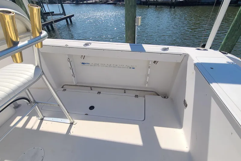 Slide: The Image of 2006 Sea Fox 287 Center Console boat interior with rod holders and storage, docked by the water. - 16