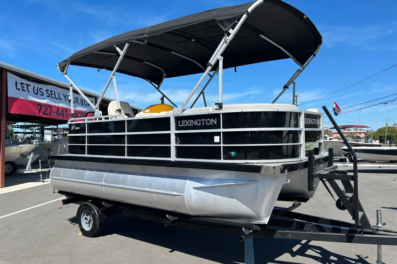 Slide: The Image of 2022 Lexington 317 series pontoon boat on trailer, displayed outdoors under clear blue sky. - 1