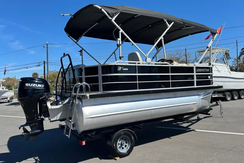 Slide: The Image of 2022 Lexington 317 series pontoon boat with Suzuki outboard motor on trailer. - 2