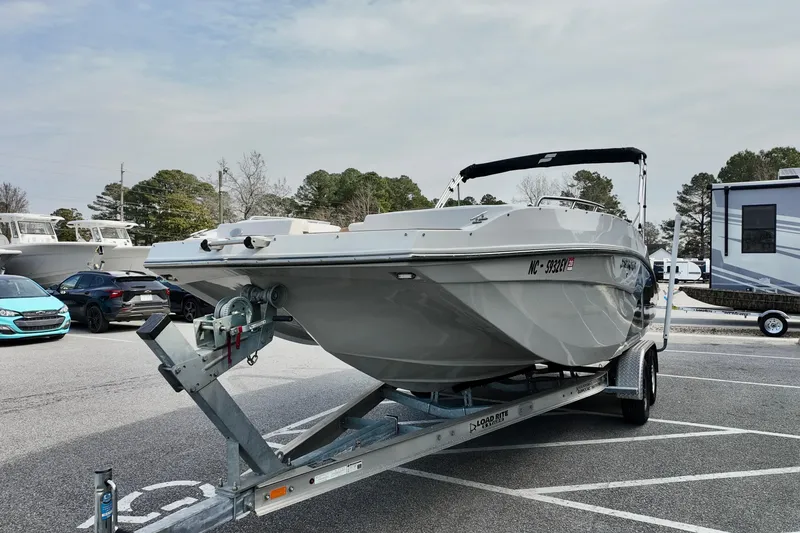 Slide: The Image of 2023 Starcraft SVX 231 OB boat on trailer in parking lot, surrounded by cars and trees. - 13