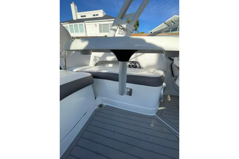 Slide: The Image of 2022 Crownline 255 SS SURF boat interior with seating and table, docked at marina. - 13