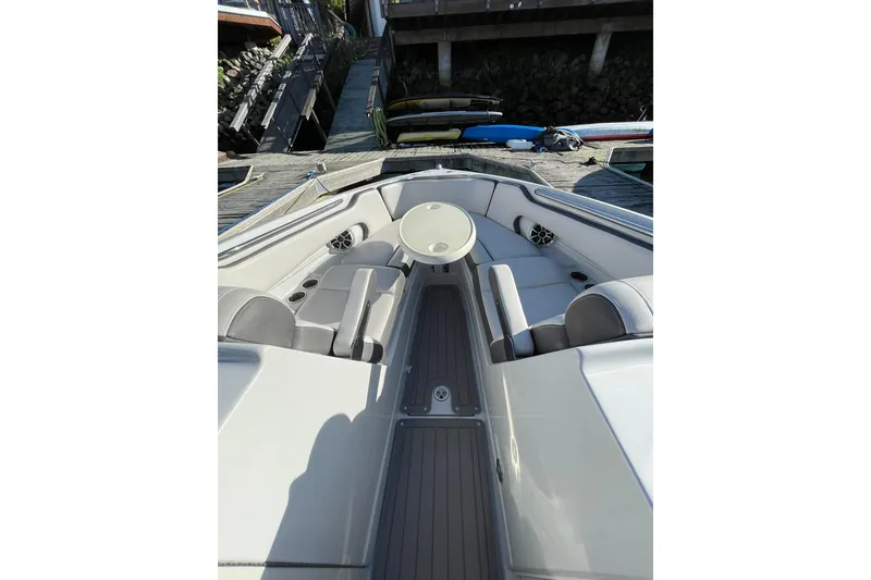 Slide: The Image of 2022 Crownline 255 SS SURF boat interior with canopy, docked in a serene marina. - 20