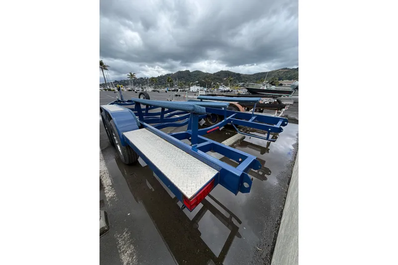 Slide: The Image of Blue boat trailer for 2022 Crownline 255 SS SURF, parked on wet pavement under cloudy skies. - 42