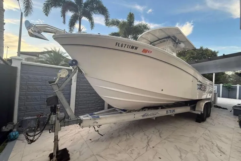 Slide: The Image of 2004 Grady-White Chase 273 boat on trailer, parked outdoors with palm trees. - 1