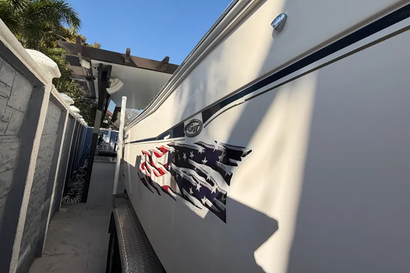 Slide: The Image of 2004 Grady White 273 boat with American flag decal, parked under a canopy. - 13