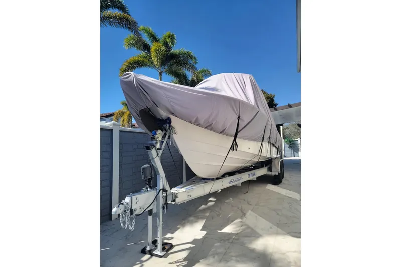 Slide: The Image of 2004 Grady-White Chase 273 boat covered on trailer, parked outdoors under clear blue sky. - 157