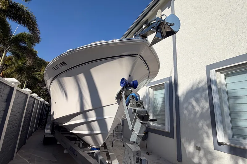 Slide: The Image of 2004 Grady White 273 boat on trailer beside a house, under clear blue sky. - 5