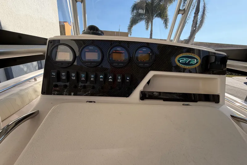 Slide: The Image of 2004 Grady White 273 boat dashboard with gauges and controls, palm trees in background. - 71
