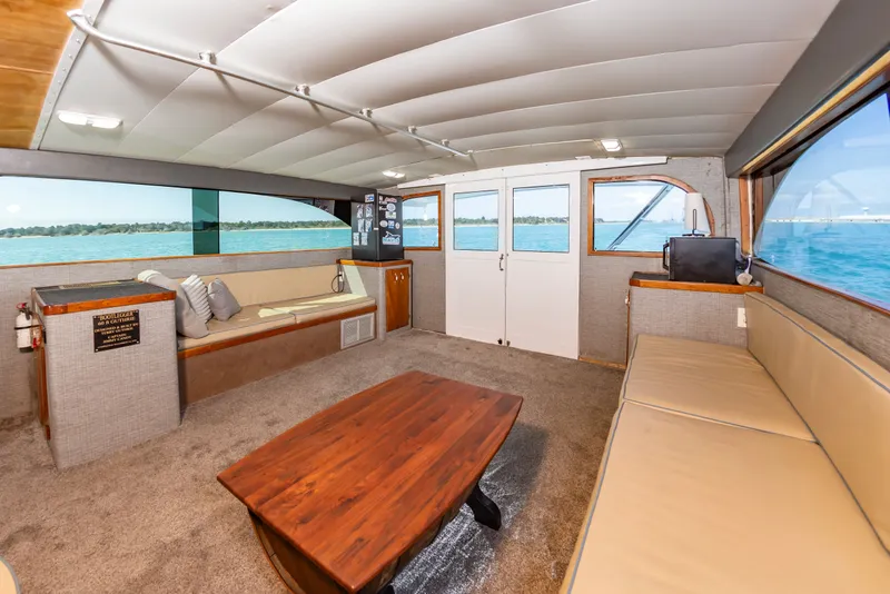 Slide: The Image of The interior of a 2000 Custom Carolina Terry Guthrie Sportfish features a cozy seating area with large windows and a wooden table. - 23