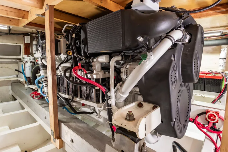 Slide: The Image of The engine room of a 2000 Custom Carolina Terry Guthrie Sportfish features a large engine with hoses and cables. - 28