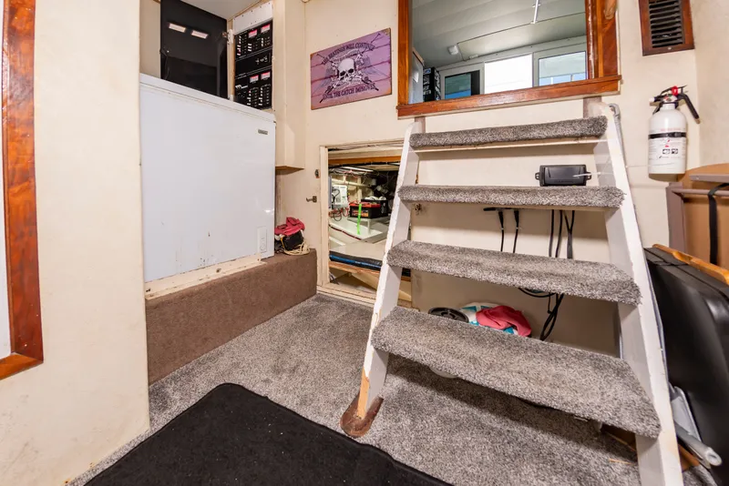Slide: The Image of Interior of a boat with carpeted stairs, fire extinguisher, and access to an engine room. - 24