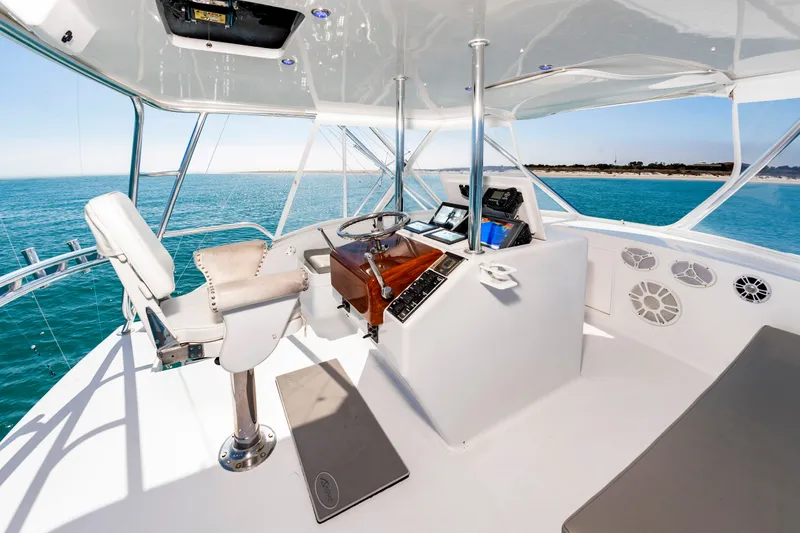Slide: The Image of The image shows the helm of a 2000 Custom Carolina Terry Guthrie Sportfish. It features a captain's chair, wooden steering wheel, and modern navigation equipment. The view of the blue sea is stunning. - 14